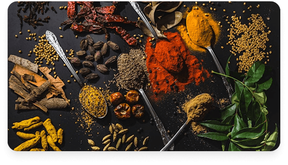 Assorted whole and ground Asian spices on a dark surface